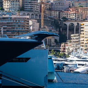Close up view of a superyacht bow, with Monte Carlo in the background.