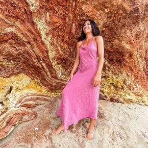 Woman in pink dress posing in front of the bay's surrounding rocks 