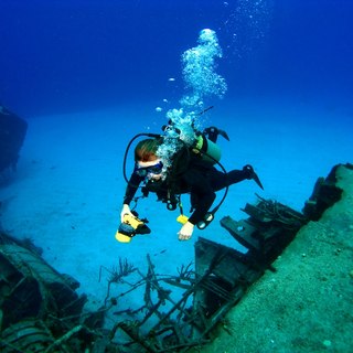 Female diver admiring the shipwreck in the bottom of the sea