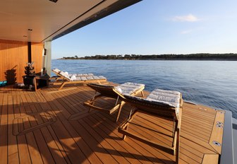 Beach club on luxury yacht PLANET NINE, with loungers lined up by the water