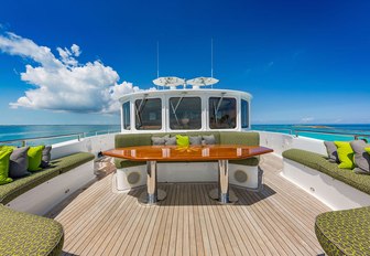 the spacious and grand sun deck of charter yacht gota with green accents, sumptuous loungers, overlooking the clear blue sky of the mediterannean