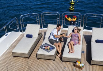 charter guests relax on sunbeds on the sundeck of luxury yacht Far From It 