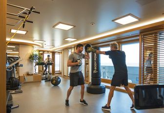 Gym onboard superyacht charter FLYING FOX with two charter guests boxing, surrounded by equipment