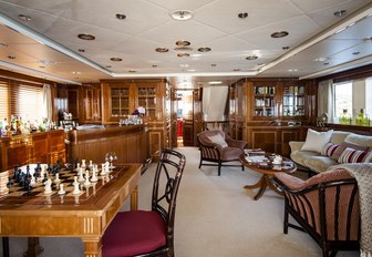 games table, seating area, bar and bookcase in the skylounge aboard luxury yacht Metsuyan IV