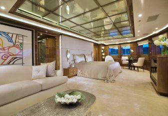 Master cabin onboard superyacht charter ALFA NERO, central berth with adjacent cream sofa and multiple windows aft