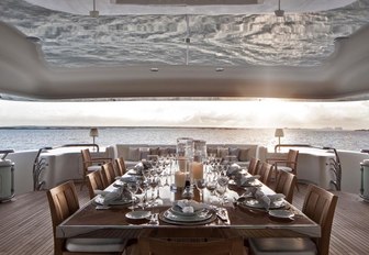 formal al fresco dining table on superyacht lady e, with sunset over sea in background