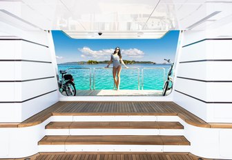 charter guests stands on swim platform looking into beach club on board charter yacht My Seanna