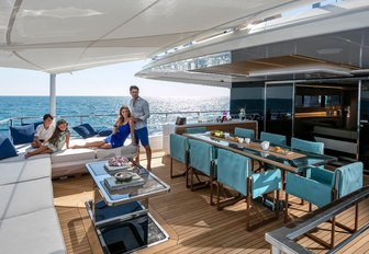 family relaxes on the deck of superyacht NAMASTE with al fresco dining area and expanse of sofas