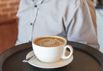 Man holds tray with latte on it at Boroughs in Yas Island, Abu Dhabi