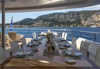 Alfresco dining option onboard SERENITY, elaborate table presentation looking out over raised terrain and sea.