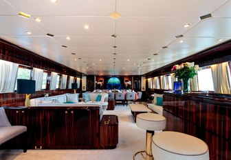 Main salon on board superyacht HEMILEA, with dining in background and bar with fresh flowers on it in foreground