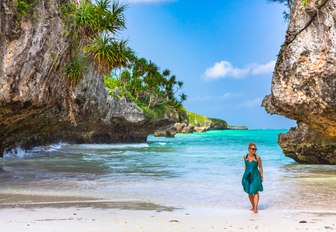 woman walks in shallows of beach in tanzania 