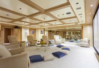 Soft seating area on O'MEGA superyacht with large screen in background