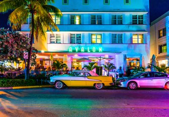 vintage cars park outside Art Deco hotel along South Beach at night