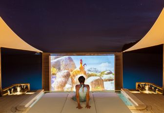 Charter guest relaxing on deck with outdoor cinema projection onboard charter yacht LIV LOVE