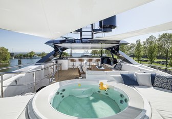 A Jacuzzi filled with water with a large and small yellow rubber duck floating on top