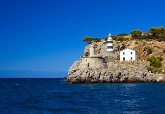 A black and white striped lighthouse on a cliff in Mallorca