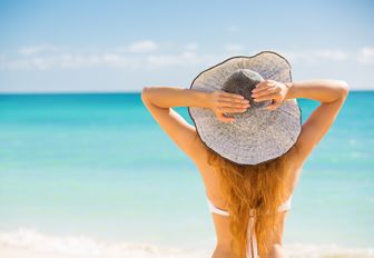 women takes in the beautiful turquoise waters on a white sand beach of the Bahamas