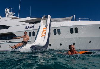 Man coming down large water slide from side of Superyacht BACA