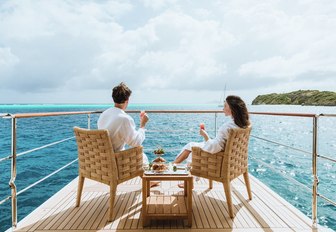 charter guests relax on the master suite's drop-down balcony aboard superyacht Ramble on Rose 