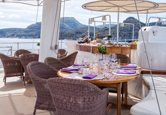 Dining area on superyacht SHERAKHAN sundeck, with two tables and spa pool in background