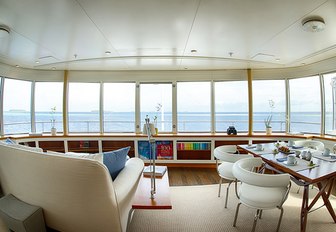 sofa and table and chairs look out to sea in a salon aboard superyacht SENSES