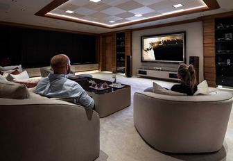 Cinema room on Superyacht LANA with two people in large chairs looking at screen