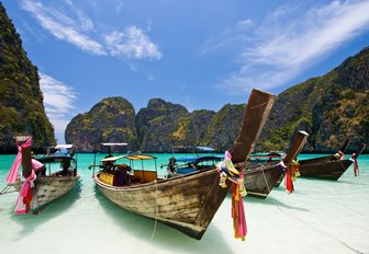 traditional Thai fishing boats line up on the white sandy shores of Maya Beach on Koh Phi Phi, Thailand