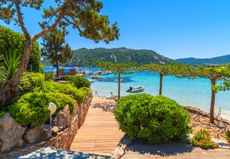 French island of Corsica, tree-lined path and views over shallow blue sea