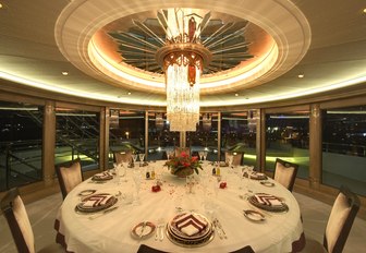 circular dining table with panoramic views and glittering chandelier on board luxury yacht AMARYLLIS 