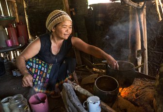 Local lady of Ngada village cooking in thatched roof cottage