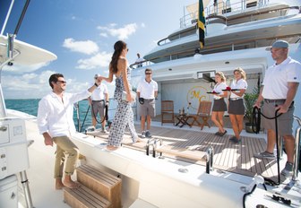 charter guests arrive onto the beach club of luxury yacht Mine Games and are greeted by the crew