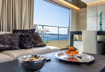 Fruit and snacks in bowls on table with sofa and large window in background of motor yacht Cinquanta 50