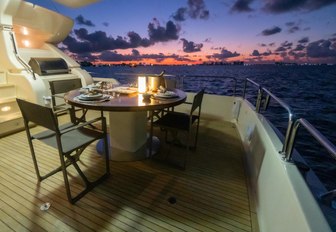 sun setting behind a romantic candlelit alfresco dining table as luxury charter yacht NOMADA makes way to Belize 