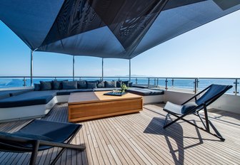 Shaded decking area on ARBEMA with wooden decking and comfortable sofa and two lounging chairs in foreground