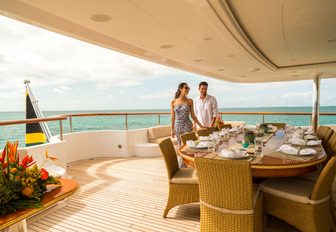 guests prepare to sit down for dinner in the al fresco dining area on board luxury yacht Lumiere II