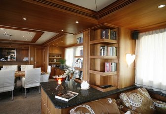 Bookshelves in main salon with formal dining in background on luxury yacht DARDENELLA