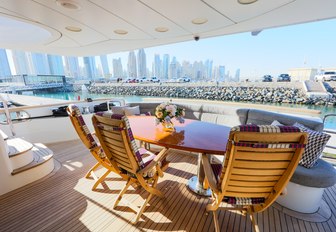 al fresco dining area on the main deck aft aboard superyacht with Dubai cityscape in the background