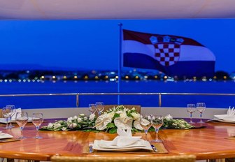 croatian flag on back of superyacht with dining in background
