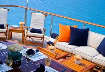 outdoor seating area with sofa, teak chairs and coffee tables on board motor yacht M4