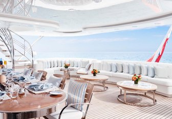 al fresco dining table and built-in sofas on the upper deck aft of charter yacht Lady E 