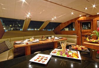 Interior dining on foredeck of motor yacht Annabel II, with curved sofas and sloping windows