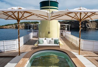 Spa pool on top deck of classic yacht, with twin parasols either side 