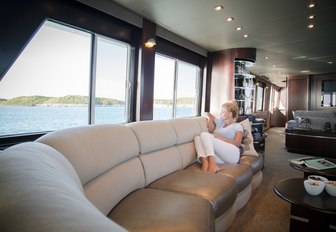 guest relaxes on the sofa in the main salon of charter yacht UNBRIDLED 