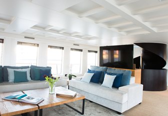 sofas in the main salon of charter yacht MENORCA with spiral staircase in view