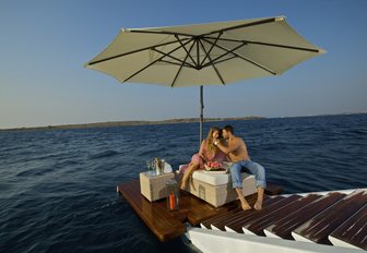 O'MEGA steps from beach club leading into ocean with two people sitting on platform at sea level