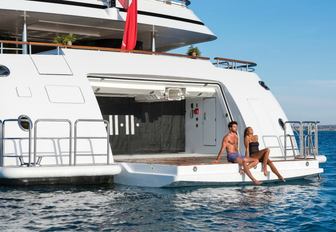 charter guests perch on edge of the drop-down swim platform aboard charter yacht 11/11 