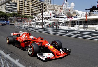 A red Ferrari F1 car passes the yacht section of the Monaco Grand Prix race track