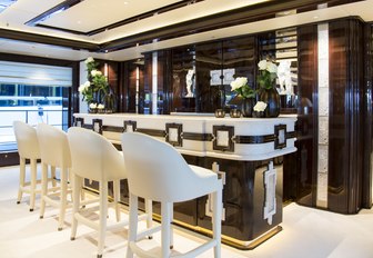 sleek bar with white bar stools in the main salon of superyacht Illusion V 