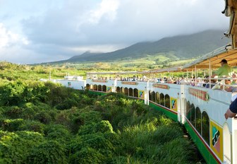 Mountain train with passengers atop traveling through the lush mountains of St Kitts and Nevis in the Caribbean